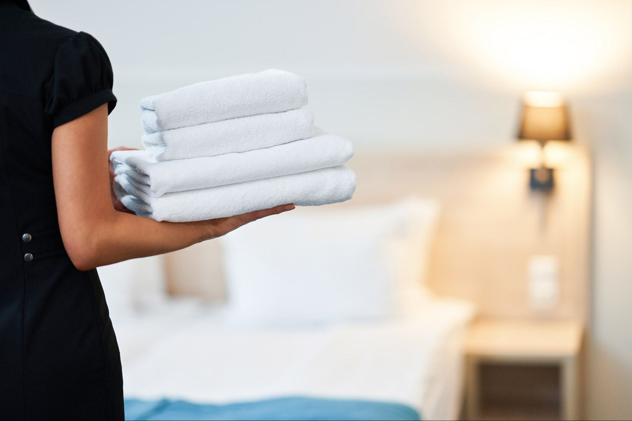 Una camarera de piso con toallas limpias en la habitación del hotel