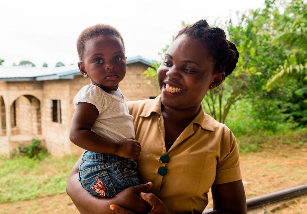 Edna Mensah, enfermera del centro de Salud de Pakro en Ghana, con una niña en brazos