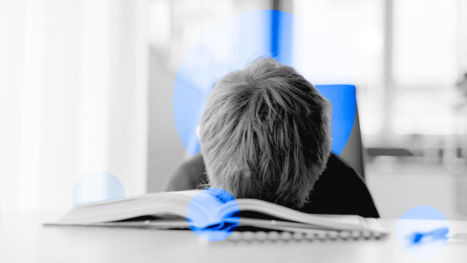Un niño con la cabeza apoyada en un libro sobre un pupitre