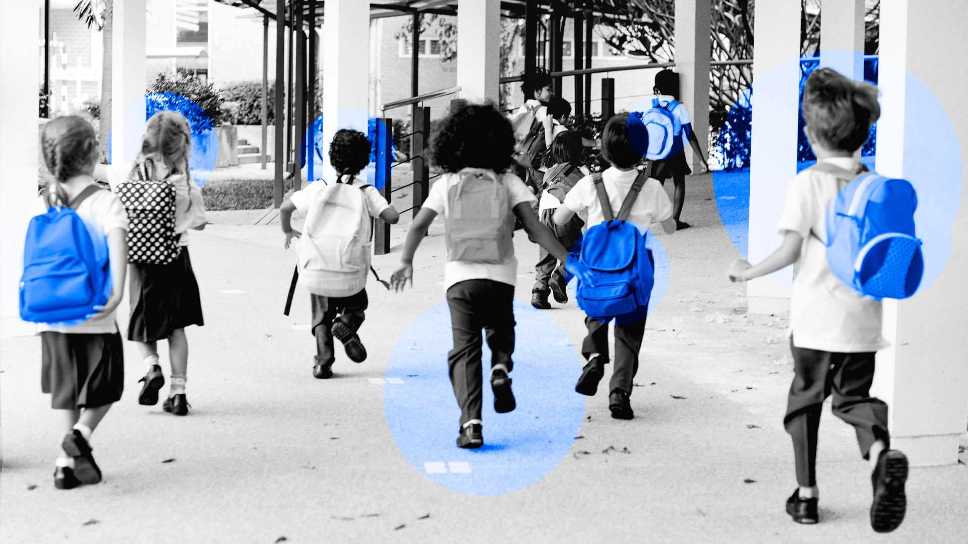 Varios niños y niñas entrando al colegio son sus mochilas