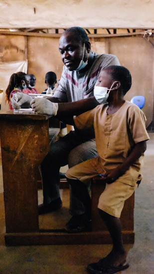 En la consulta ambulante organizada en la escuela de Davié, un médico coge una muestra de sangre de un niño sospechoso de tener pian