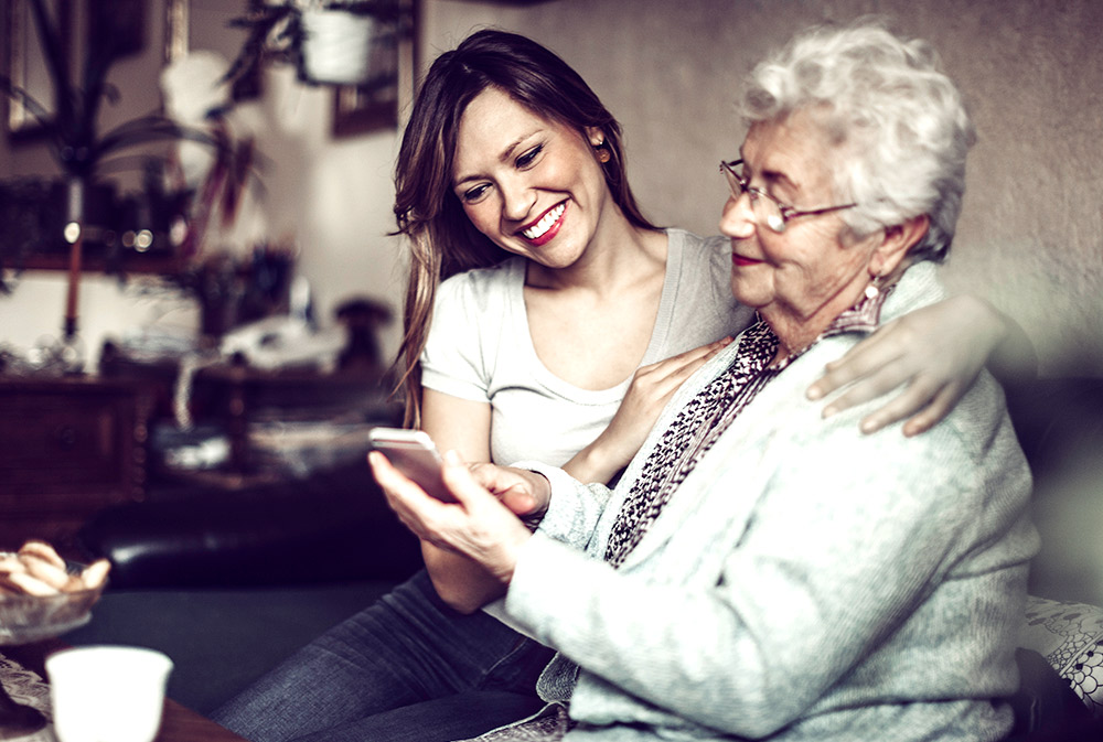 Una mujer joven ayudando a una mujer mayor con su teléfono móvil | © Getty Image, Telefónica