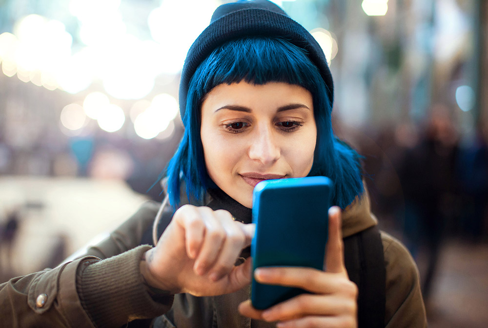 Una mujer joven interactuando con su teléfono móvil | © Getty Image, Telefónica