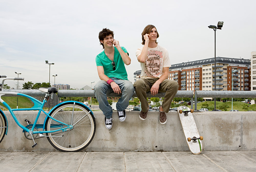 Dos jçovenes hablando por su teléfono móvil en la calle | © Getty Image, Telefónica